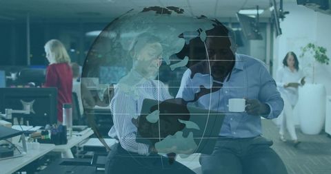 Collaborating over laptop in modern open office with digital globe overlay signaling global teamwork