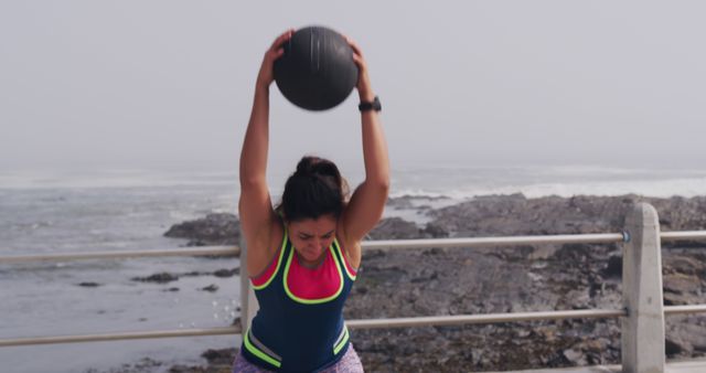 Determined Woman Working Out with Medicine Ball Outdoors by Ocean - Download Free Stock Images Pikwizard.com