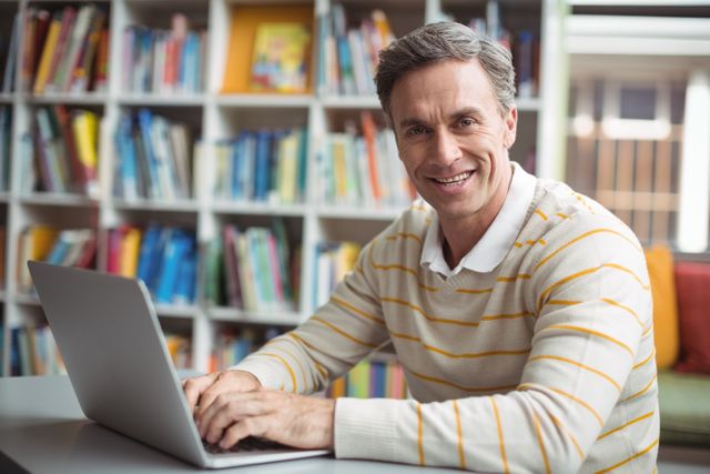 Portrait of happy school teacher using laptop in library - Download Free Stock Photos Pikwizard.com