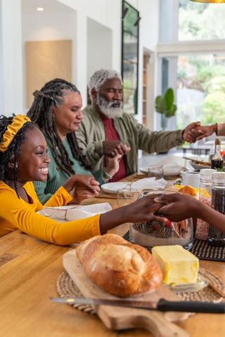 African american family holding hands and praying around holiday dinner table