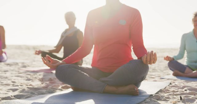 People participating in a group yoga session on the beach at sunset. Ideal for illustrating themes of relaxation, group fitness, mindfulness, meditation, and healthy lifestyles. Useful for wellness blogs, fitness websites, meditation apps, outdoor activity promotions, and holistic health advertisements.