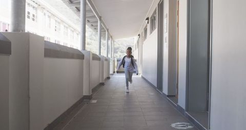 Energetic Student Running in School Corridor with Backpack