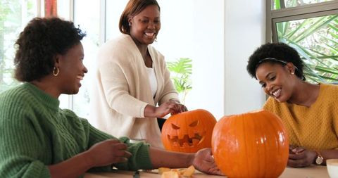 Friends Enjoying Pumpkin Carving During Cozy Autumn Gathering