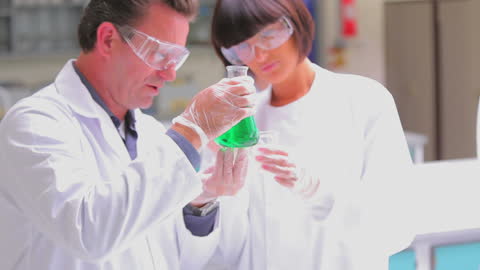Two Scientists Analyzing Green Liquid in Laboratory