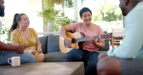 Diverse Group of Friends Relaxing at Home with Live Music