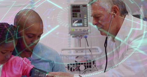 Pediatrician examining child while father holding arm with bp cuff and vital monitor