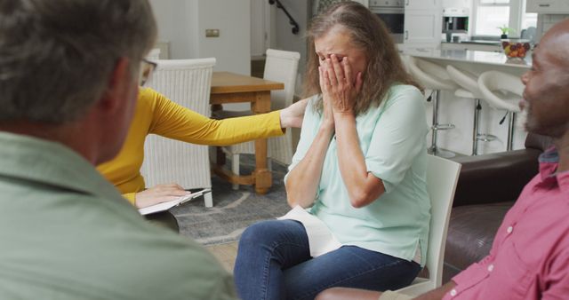 A woman experiencing distress is comforted by members of a support group in a home-like environment. This can be used in materials related to mental health, therapy sessions, and emotional recovery. It emphasizes themes of compassion, community support, and psychological care.