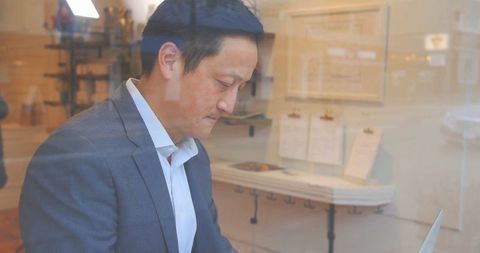 Focused Businessman Typing at Office Counter by Large Window