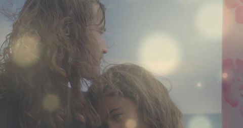Windblown embrace on coastal shoreline with soft lens flare and patterned panel