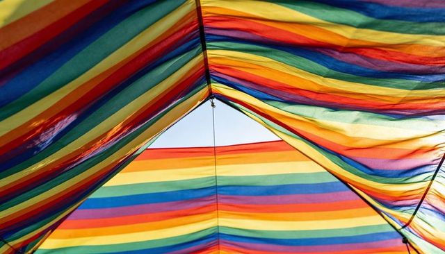 Vibrant backlit rainbow canopy with striped translucent fabric and central triangle opening