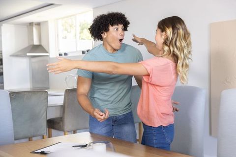 Young couple sharing surprise hug in sunlit modern kitchen celebrating new home