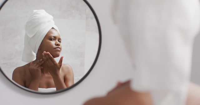 Happy african american woman apply cream on face in bathroom - Download Free Stock Photos Pikwizard.com