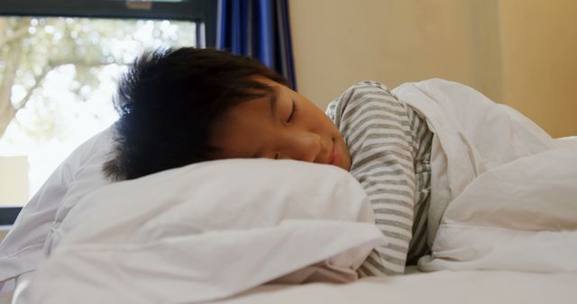 An Asian child is peacefully sleeping in bed, with copy space. Capturing a moment of rest, the image conveys a sense of tranquility and comfort.