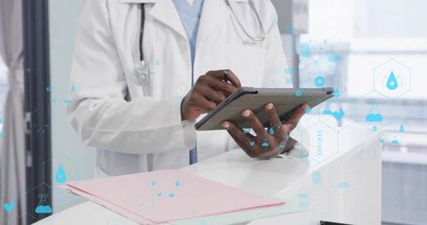 Doctor using tablet with stylus at clinic showing telemedicine icons and digital records