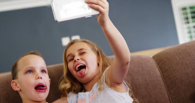 Boy and girl talking a selfie on mobile phone in living room