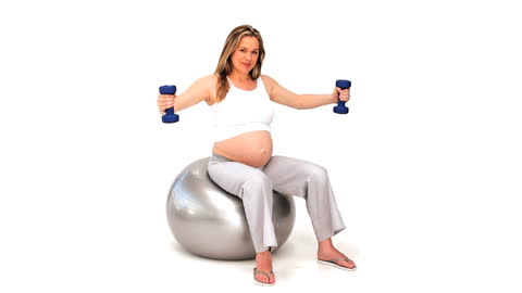 Pregnant Woman Exercising on Stability Ball with Dumbbells
