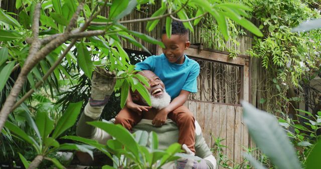 Grandfather and grandson smiling and enjoying time in garden surrounded by greenery. Great for family unity, nature appreciation, intergenerational relationships, and health and wellness themes.