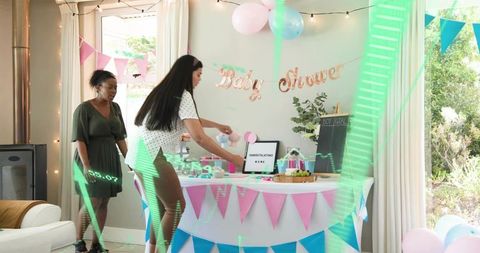 Women arranging pastel baby shower table with bunting, balloons, cakes and party decor