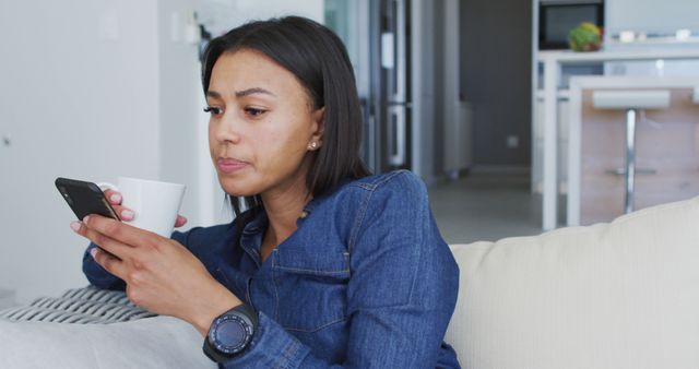 Woman Relaxing on Sofa Looking at Smartphone and Drinking Coffee - Download Free Stock Images Pikwizard.com