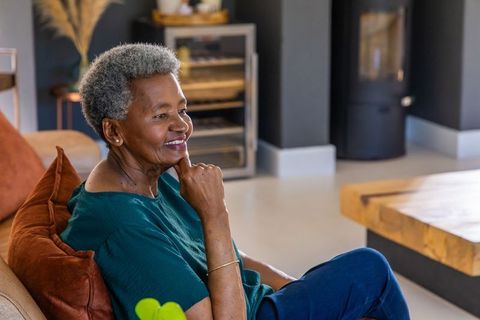 Senior african american woman smiling and relaxing on modern living room sofa