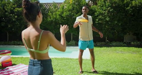 Mixed Race Friends Enjoying Frisbee Game By Backyard Pool