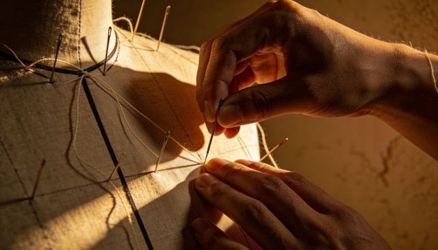 Tailor Hands Pinning Canvas Dress Form Pattern Lines under Warm Golden Light