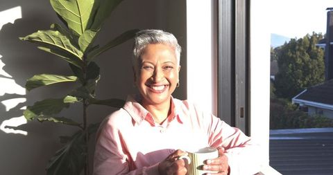 Senior Woman Relaxing with Mug by Sunlit Window