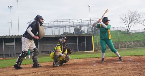 Softball game action at home plate under stadium lights