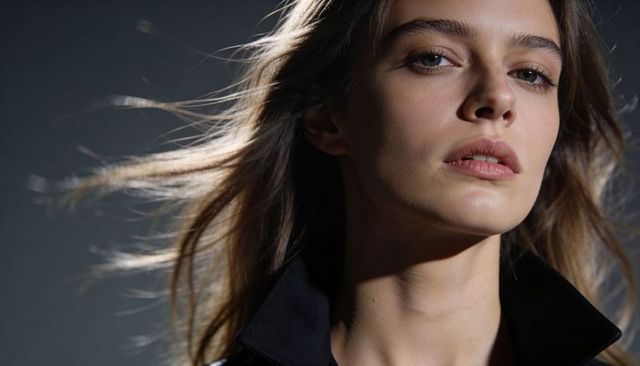 Windblown closeup portrait female model posing gazing right dramatic high-contrast lighting