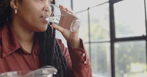 Woman Enjoying Refreshing Glass of Water by Window - Download Free Stock Images Pikwizard.com