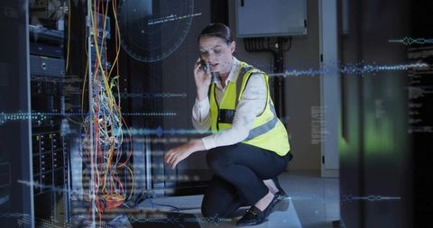 Data center technician checking server cables and calling while wearing reflective vest