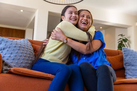 Mother and Daughter Embracing Joyfully on Vibrant Sofa