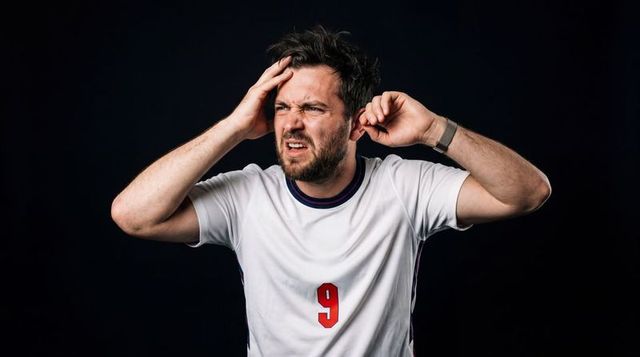 Tense man holding head pressing ear in white sports jersey number 9 showing headache