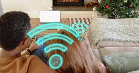 Couple relaxing on couch streaming laptop with wi-fi icons and cozy christmas fireplace