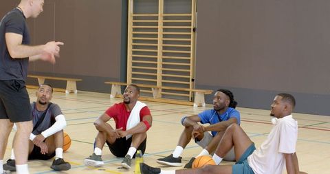 Coach leading basketball team huddle during indoor training session for teamwork motivation