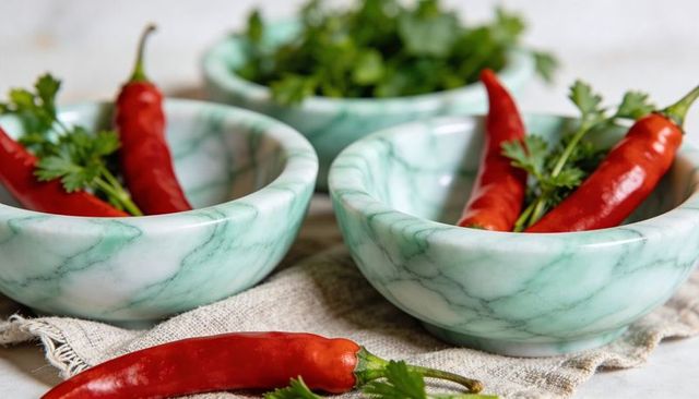 Green marble bowls with red chilies and cilantro on linen rustic kitchen ingredients