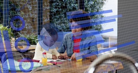 Caregiver guiding child drawing at wooden table with blue charts overlay, education and creativity