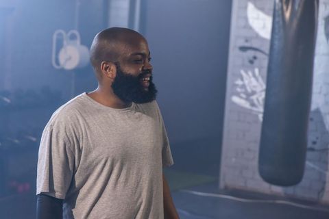 African american man smiling after boxing workout in urban gym with punching bag