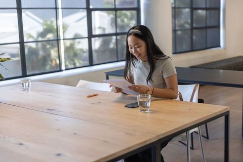 Asian Businesswoman Reviewing Documents in Modern Office Space