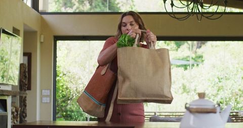 Pregnant woman carrying weighty reusable bags after grocery shopping