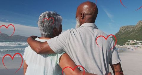 Elderly Couple Enjoying Romantic Beach Time with Falling Hearts