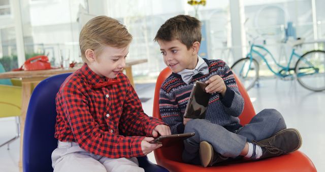 Two Boys Sitting and Sharing Digital Devices in Modern Room - Download Free Stock Images Pikwizard.com