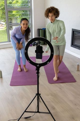 African american women recording home workout with ring light on purple yoga mats