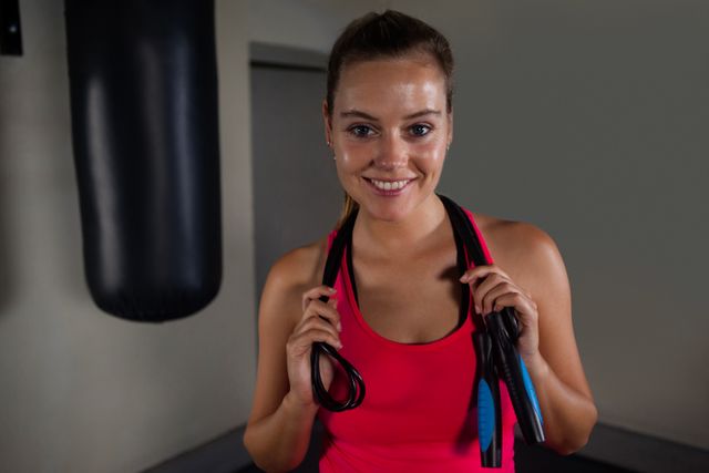 Portrait of fit woman standing with skipping rope in fitness studio