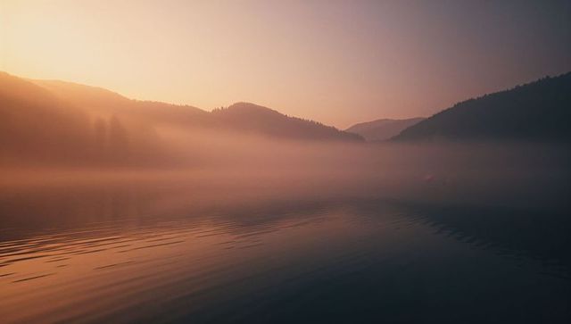 Dreamlike Mist Over Lake at Sunrise with Mountain Silhouette