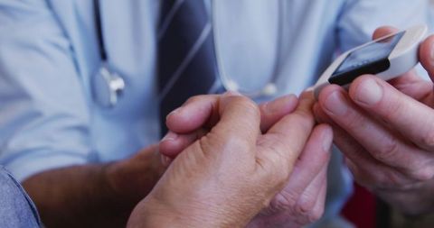 Doctor Measuring Blood Sugar of Senior Patient for Diabetes Health Care