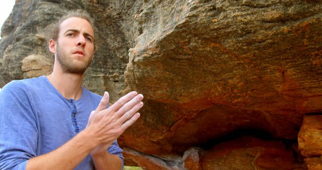 Man standing next to large rock formation using climbing chalk for better grip, suggesting he is about to pursue rock climbing or bouldering. Ideal for content related to outdoor sports, adventure activities, fitness, and exploration.