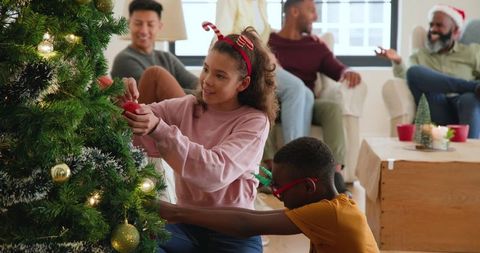 Diverse Family Decorating Living Room Christmas Tree in Cozy Atmosphere