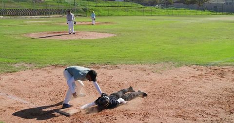 Sliding headfirst baseball tag at home plate dusty infield action with glove helmet