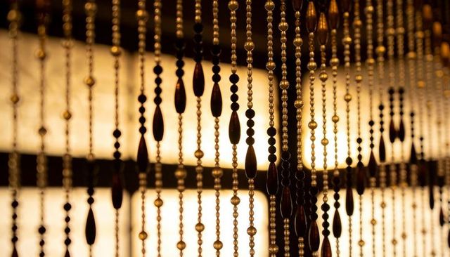 Backlit amber beaded curtain strands with teardrop beads and repeating silhouette pattern